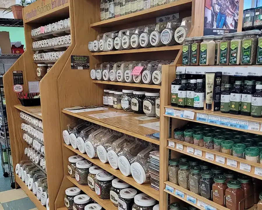 Shelves of bulk spices, dried herbs, and vanilla extract in glass jars at Food Fantasies natural foods store near Sherman, IL
