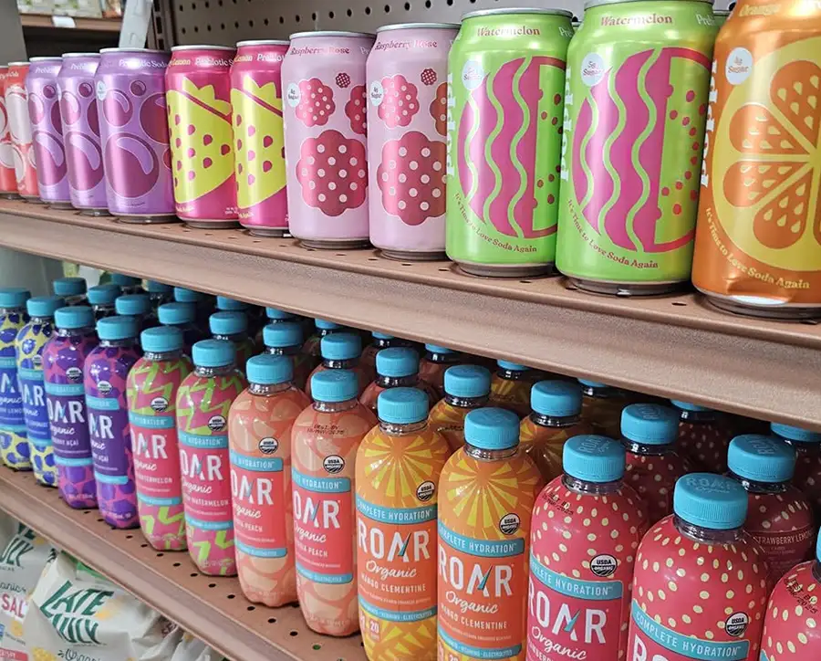 Colorful cans and bottles of sparkling prebiotic soda and organic sports drinks on a shelf at Food Fantasies near Sherman, IL